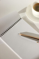 Business Meeting Mockup. Spiral Notebook with Pen and Pencil, Cup of Coffee on White Office Desk. 
