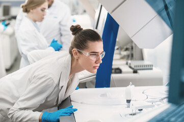 female scientist working in a modern equipped computer laboratory analyzes blood samples and...
