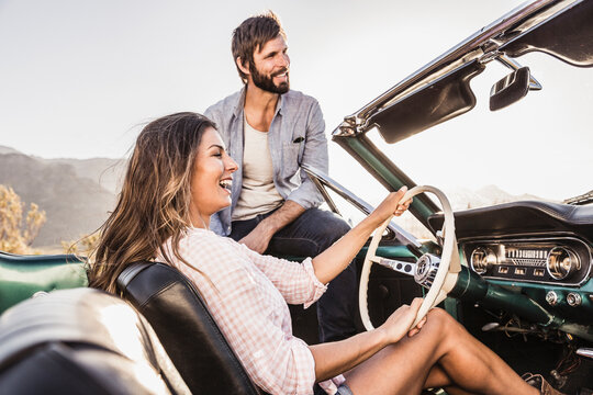 happy couple having fun during a drive in the countryside with a vintage convertible