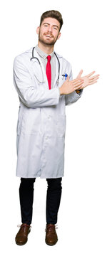 Young handsome doctor man wearing medical coat Clapping and applauding happy and joyful, smiling proud hands together