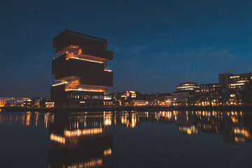 Art museum building on the riverbank in the centre of Antwerp lit up at night. Modern part of the...