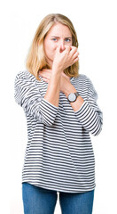 Beautiful young woman wearing stripes sweater over isolated background smelling something stinky and disgusting, intolerable smell, holding breath with fingers on nose. Bad smells concept.