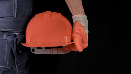 An engineer or handyman holds an orange hard hat. Close-up. Civil Engineering. Place for text.