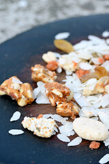 closeup the mix snack food drilled rice coconut,raisins,peanut ,sesame seeds in the wooden on the grey brown background.