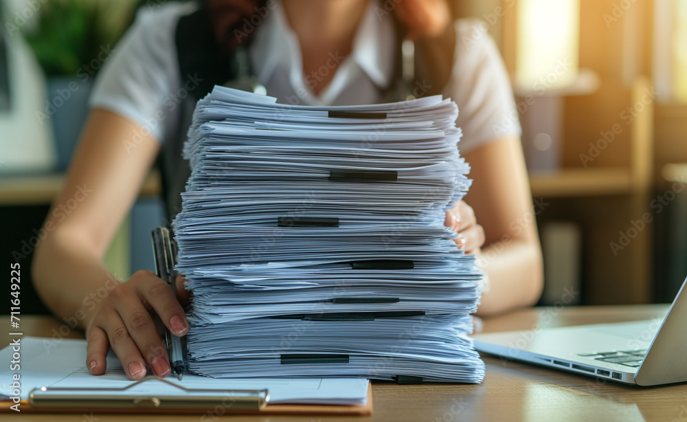 Poster stacks of paper files for searching information on work desk in office.