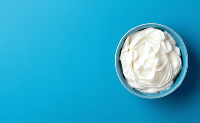 Top view of bowl with white quark or cream on side of blue background,