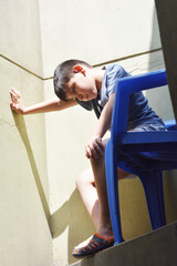 Thoughtful kid sitting on the plastic chair.