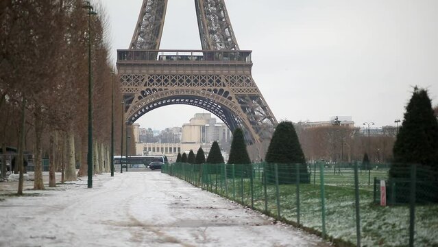 Scenic view to the Eiffel tower on a snowy day. Thin layer of snow on the ground