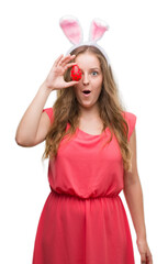 Young blonde woman wearing easter bunny ears scared in shock with a surprise face, afraid and excited with fear expression