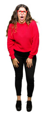 Young beautiful woman wearing red glasses afraid and shocked with surprise expression, fear and...