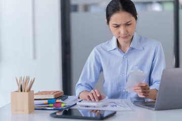 Asian businesswoman sitting in the office and be serious with her credit card bill.