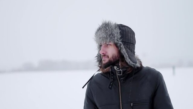 a bearded man in earflaps and snow