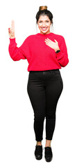Young beautiful woman wearing red sweater and bun Swearing with hand on chest and fingers, making a...