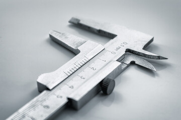 Close-up of a mechanical caliper on a light background.