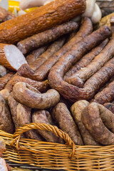 Fresh prepared smoked sausages with spices in wicker basket on market stall