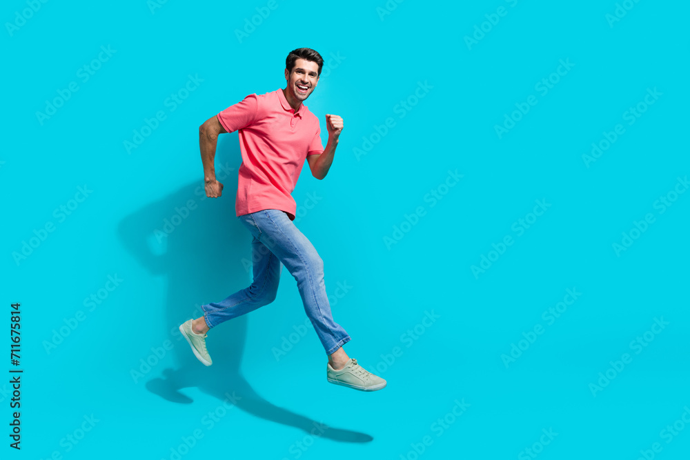Poster full length photo of attractive funky guy dressed pink polo running fast jumping empty space isolate