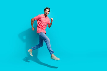 Fototapeta na wymiar Full length photo of attractive funky guy dressed pink polo running fast jumping empty space isolated blue color background