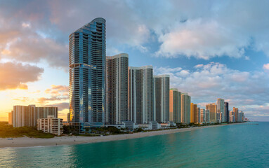 Fototapeta na wymiar Evening landscape of sandy beachfront in Sunny Isles Beach city with luxurious highrise hotels and condo buildings on Atlantic ocean shore. American tourism infrastructure in southern Florida