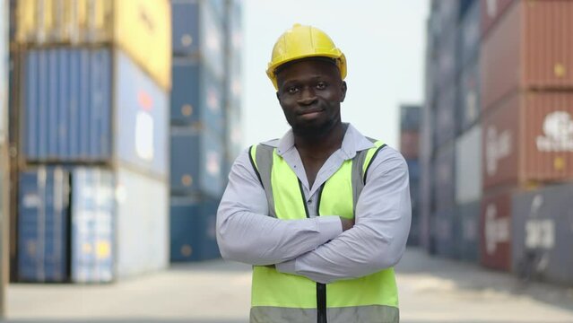 Portrait of african american container male worker or dock foreman confident  and smiling standing at warehouse logistic in Cargo freight ship for import export in harbor, happy employee arms crossed