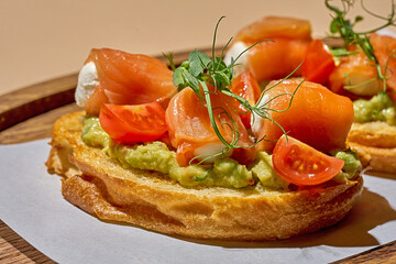 Bruschetta with bacon and guacamole on a wooden plate on a light background