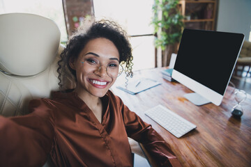 Photo of attractive cheerful banker lady sit chair make selfie empty space display workstation desk...