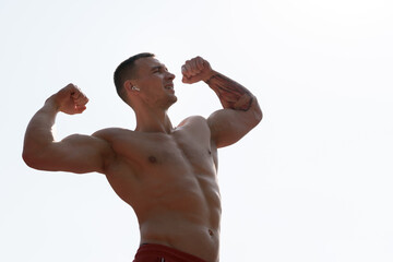 A shirtless man proudly shows off his strong muscles while basking in the sunshine.