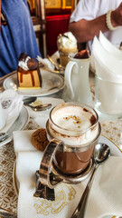 Close up of a cup of coffee in a glass cup in a formal setting.