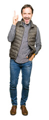 Middle age handsome man wearing winter vest pointing finger up with successful idea. Exited and happy. Number one.