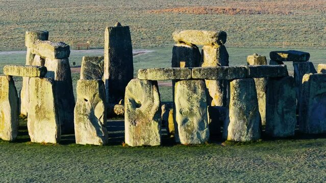 Low telephoto drone shot circling Stonehenge with a low sun and long shadows