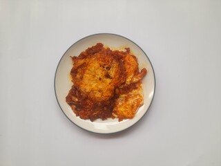 food fried egg (telur ceplok) balado with chili sauce on a plate on a white background. background concept of healthy food, food recipe, dish, meal, cuisine, ingredient, gourmet,breakfast, lunch, cook