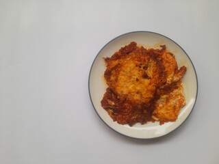 food fried egg (telur ceplok) balado with chili sauce on a plate on a white background. background concept of healthy food, food recipe, dish, meal, cuisine, ingredient, gourmet,breakfast, lunch, cook