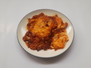 food fried egg (telur ceplok) balado with chili sauce on a plate on a white background. background concept of healthy food, food recipe, dish, meal, cuisine, ingredient, gourmet,breakfast, lunch, cook
