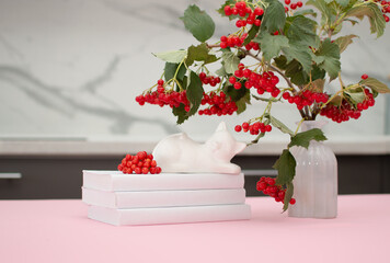 bouquet of red rowan berries on table in vase against background of white kitchen.