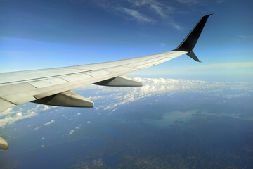 Obraz premium View through airplane window of commercial jet plane wing flying high in the sky. Air travelling concept