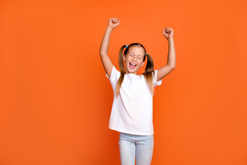 Photo portrait of pretty small girl raise fists celebrate scream lottery dressed stylish white outfit isolated on orange color background