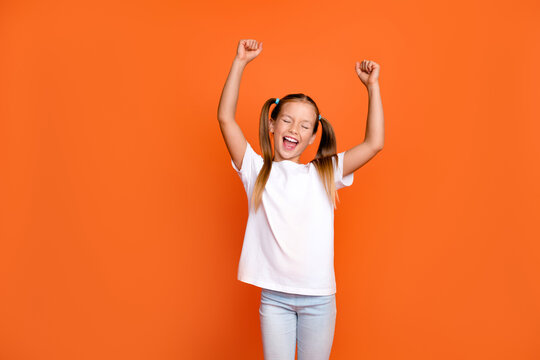 Photo Portrait Of Pretty Small Girl Raise Fists Celebrate Scream Lottery Dressed Stylish White Outfit Isolated On Orange Color Background