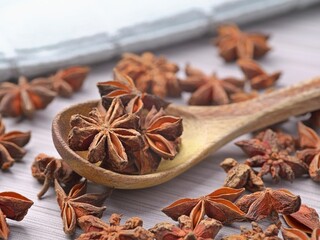 Dried star anise in a spoon and on a table.