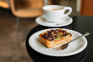 A sweet dessert toped with caramel, cranberries and seeds and a cup of black coffee