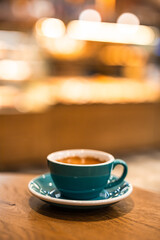 Cup of black coffee on the edge of a wooden table in a cafe coffee-shop with copy space