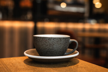 Cup of black coffee on the edge of a wooden table in a cafe coffee-shop with copy space