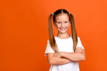 Photo portrait of pretty small girl crossed hands confident pose dressed stylish white outfit isolated on orange color background