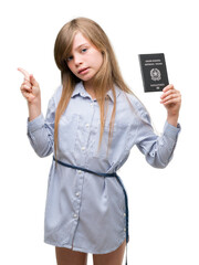 Obraz premium Young blonde toddler holding italian passport very happy pointing with hand and finger to the side
