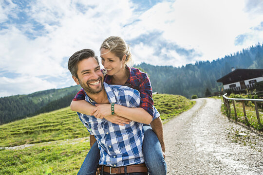 glückliches Paar in Karohemden Huckepack in den Bergen, Österreich