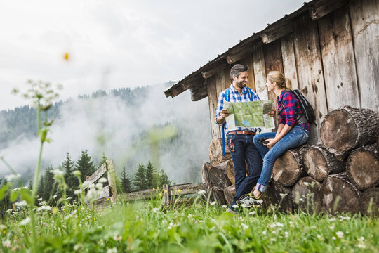 gl&uuml;ckliches Paar in Karohemden  mit Landkarte an einer Alm in den Bergen, &Ouml;sterreich
