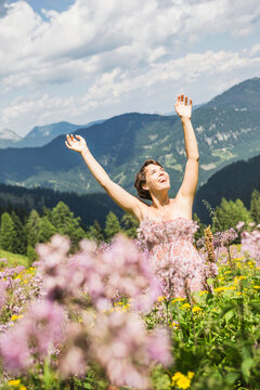 Frau tanzt vor Freude in Blumenwiese in den Bergen, &Ouml;sterreich