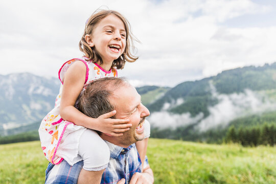 family father and daughter having fun hiking in the mountains on the shoulder
