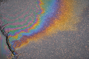 Leakage of oil or gasoline from a car onto a wet asphalt road.