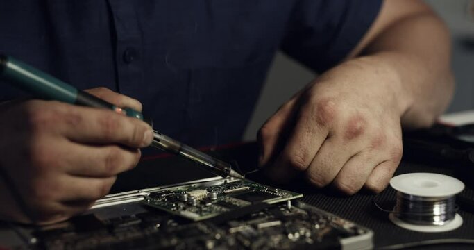 Motherboard, soldering and hands of person fixing equipment, electronics or semiconductor. Information technology, workshop or closeup technician welding circuit board, hardware or PC system at night
