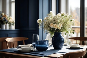 Beautiful dark blue vase with white flowers bouquet on table in modern living room interior in sunshine day
