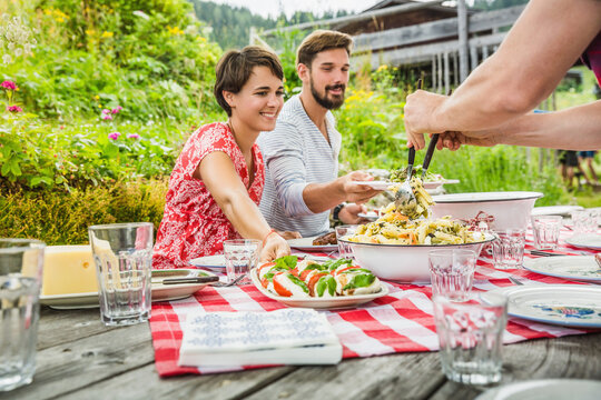 Freunde beim Essen auf Terrasse einer H&uuml;tte in den Bergen, Falkenmossalm, &Ouml;sterreich